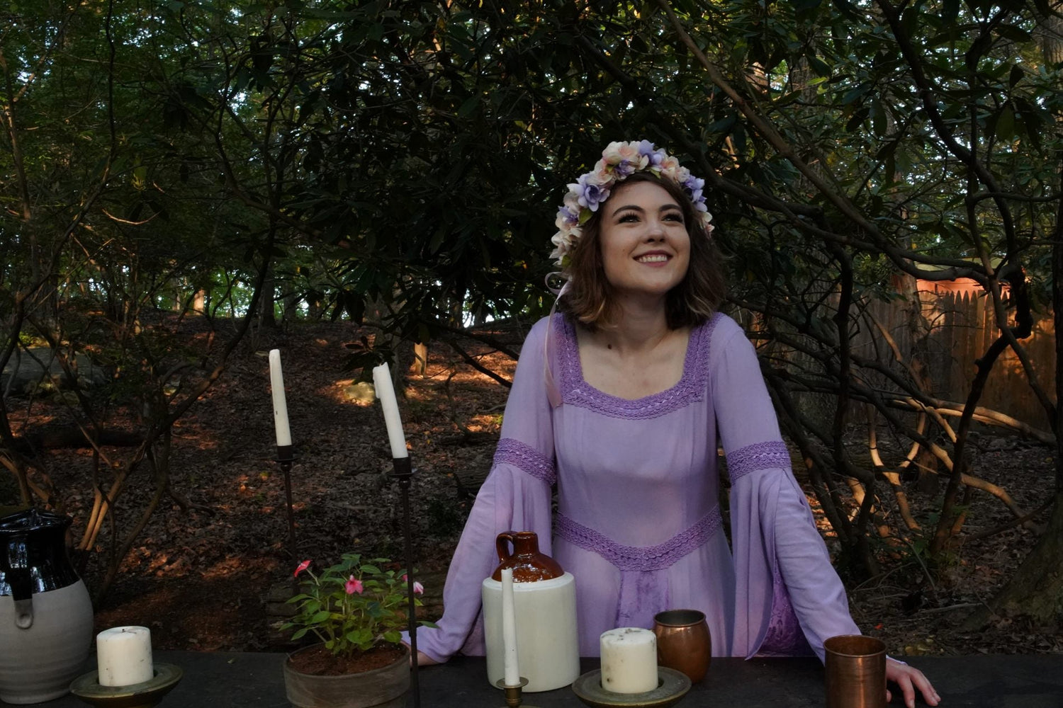 woman wearing purple renaissance dress while leaning on a wooden table