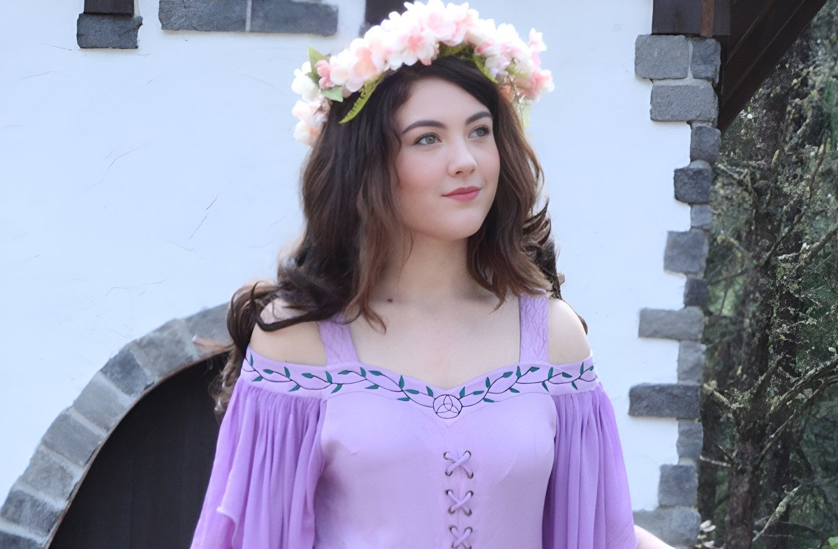 beautiful young woman wearing a purple renaissance dress and flowers on her head
